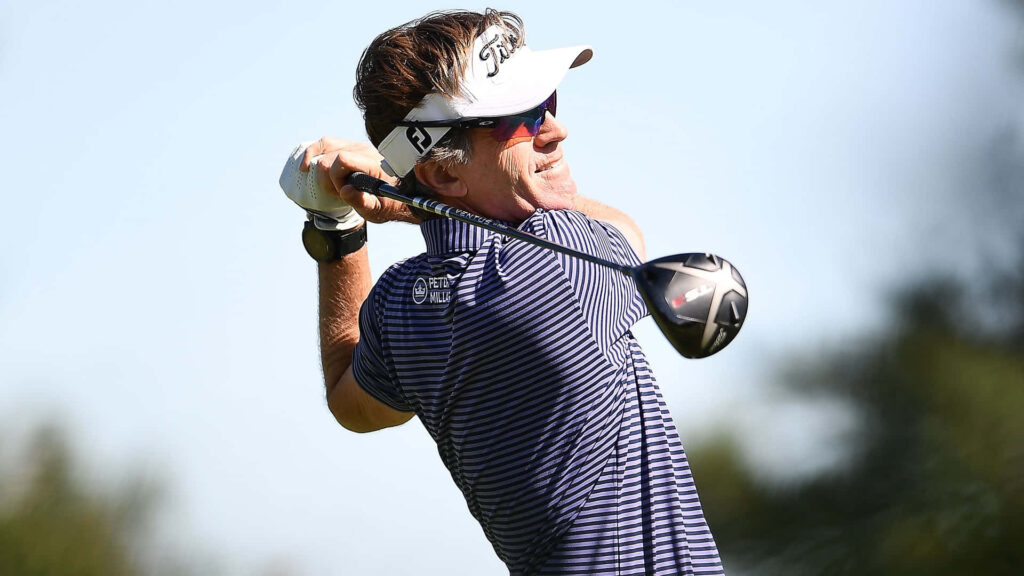 Brett Quigley perfect golf swing follow through on sunny course with clear blue sky background Wallpaper