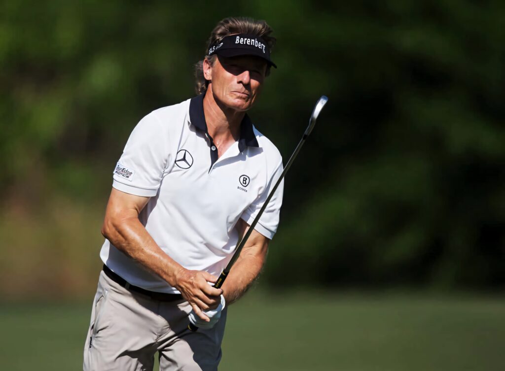 Brett Quigley focused on golf course holding golf club with lush green background wallpaper