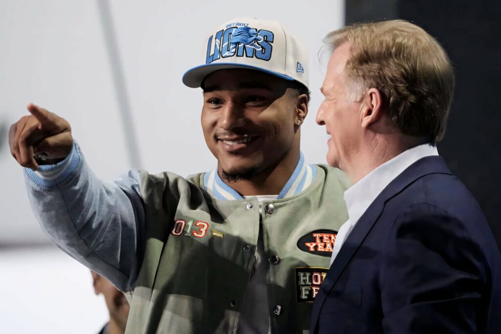 Brian Branch NFL rookie celebrating draft wearing Detroit Lions cap and letterman jacket wallpaper