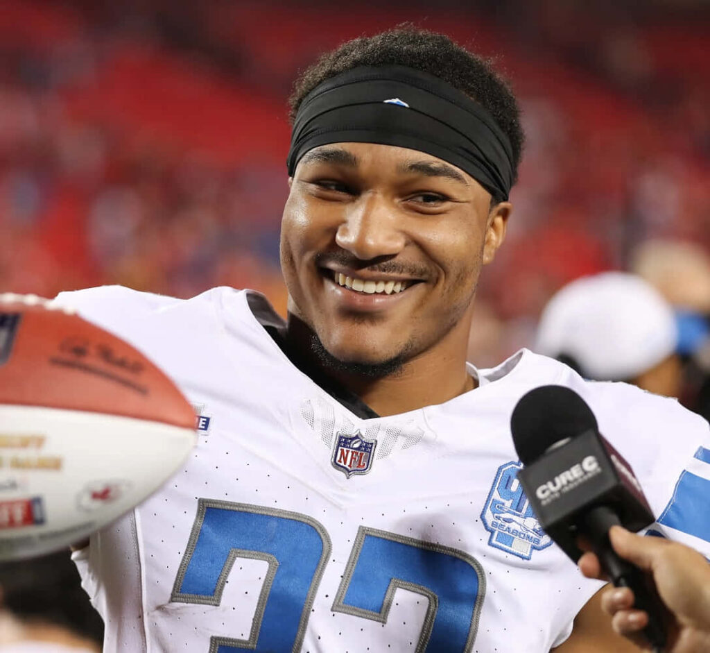 Brian Branch Detroit Lions smiling post-game on field vibrant lighting dynamic NFL wallpaper background