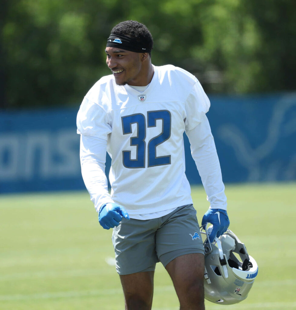 Brian Branch Detroit Lions safety in white gray jersey number 32 on sunlit practice field wallpaper