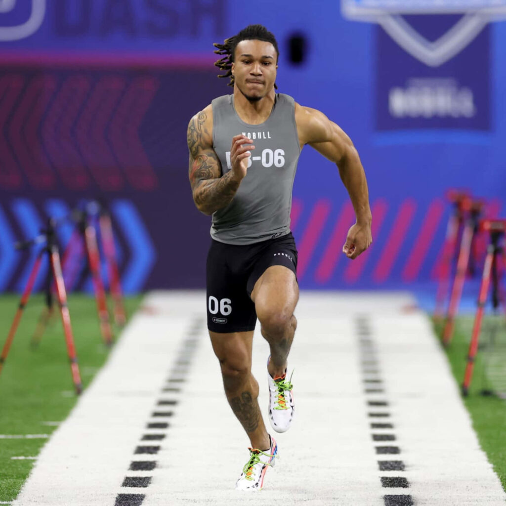 Brian Branch sprinting at NFL Combine showing speed determination athletic build stadium background Wallpaper