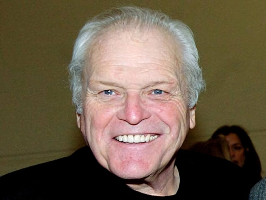 Brian Dennehy smiling warmly on soft brown background wallpaper highlighting his charisma