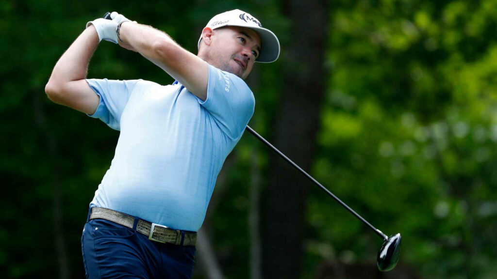 Brian Harman mid-swing on lush green golf course wearing Callaway cap golf wallpaper background