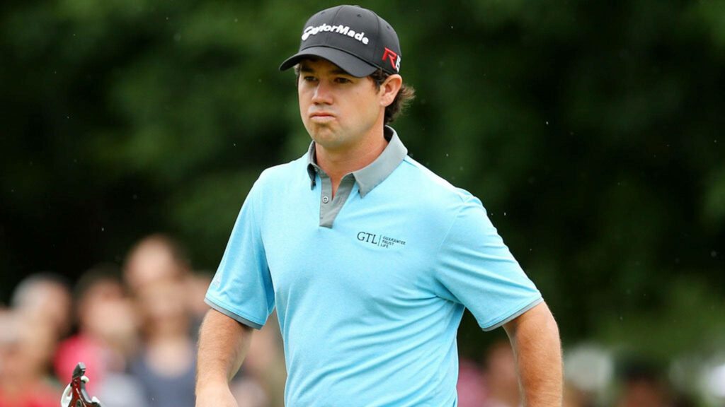 Brian Harman playing golf in light blue polo and black cap on lush green golf course background Wallpaper