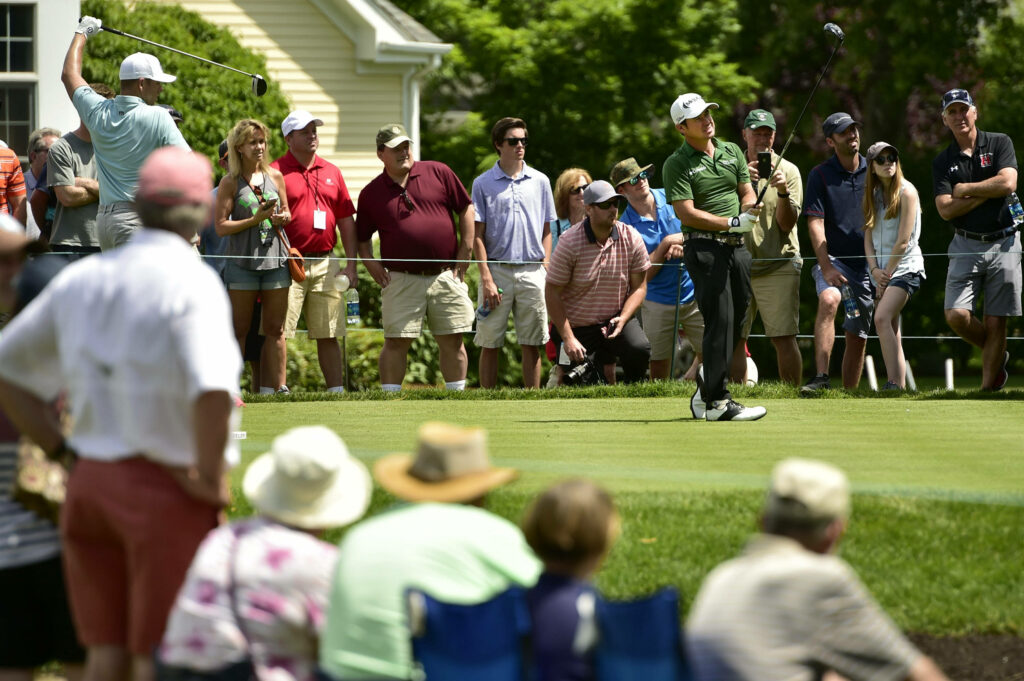 Brian Harman mid-swing tee shot on green golf course with spectators in bright daylight wallpaper