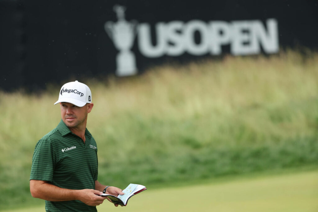 Brian Harman US Open golfer reading course booklet in green polo on golf course wallpaper background