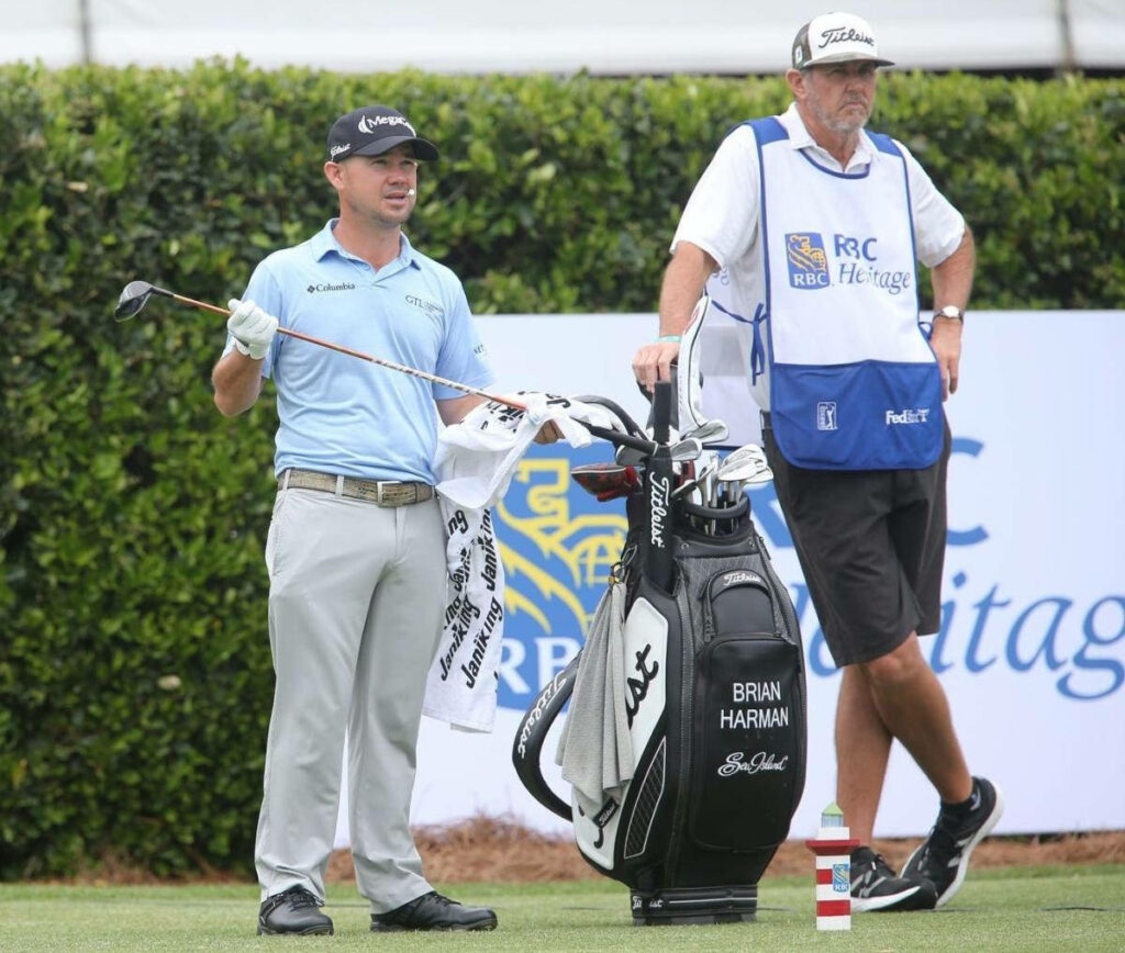 Brian Harman with caddy standing by black golf bag at RBC Heritage tournament green background Wallpaper