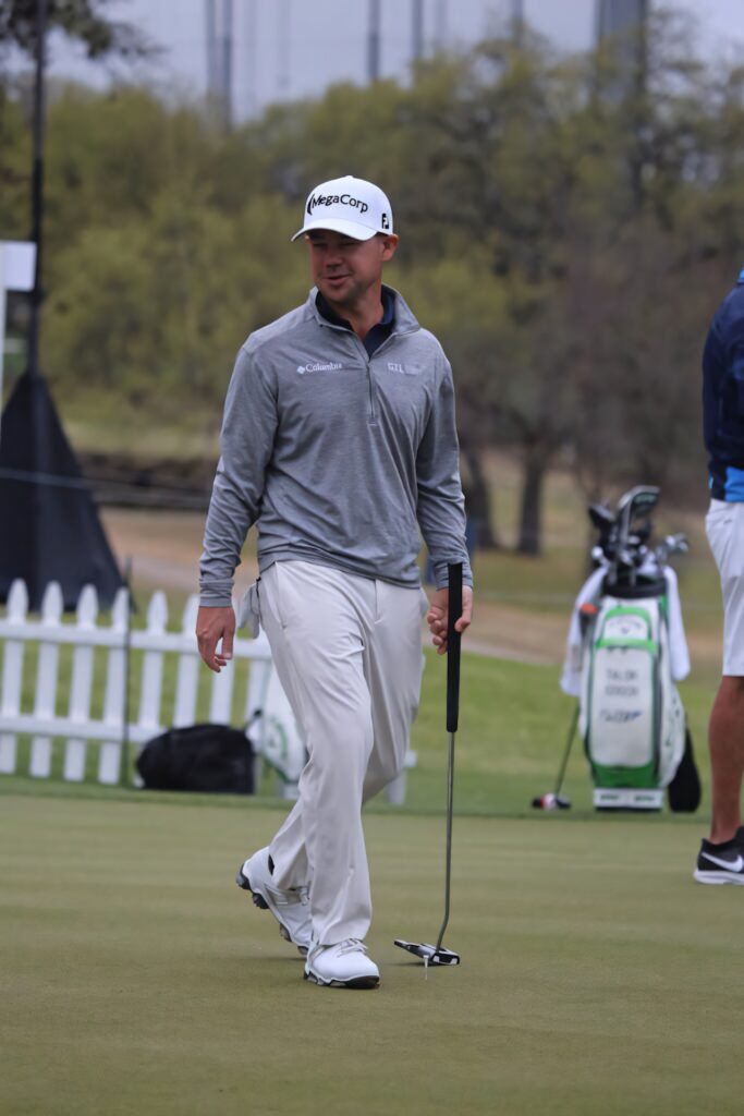 Brian Harman walking on green golf course golf wallpaper with putter and golf equipment background
