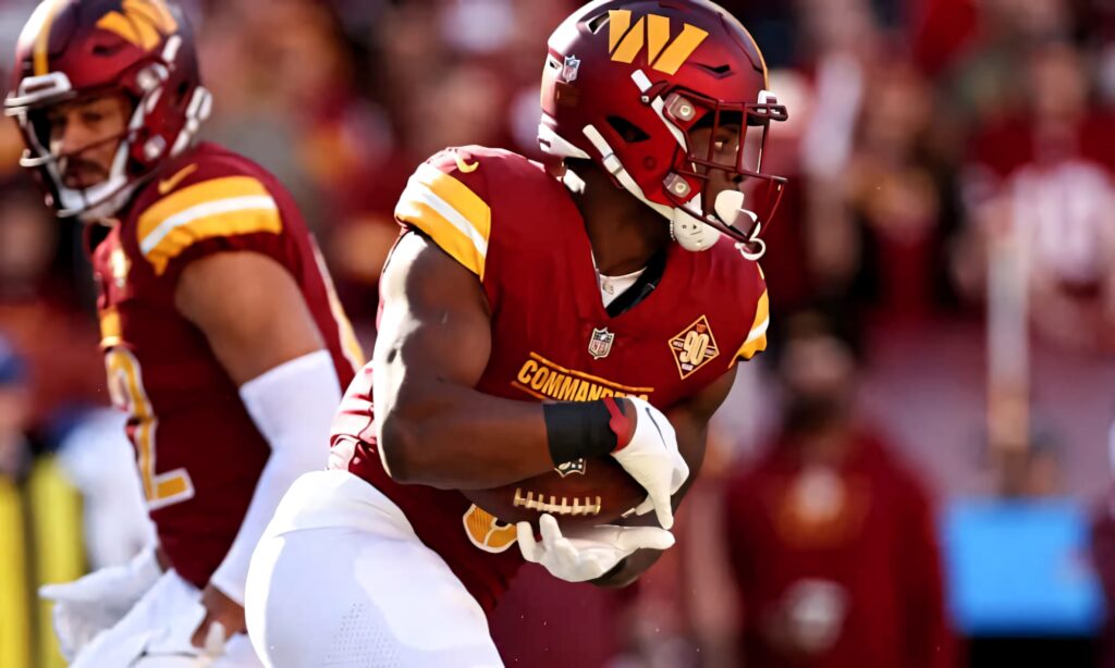 Brian Robinson Jr NFL running back in burgundy gold uniform intense focus stadium action wallpaper