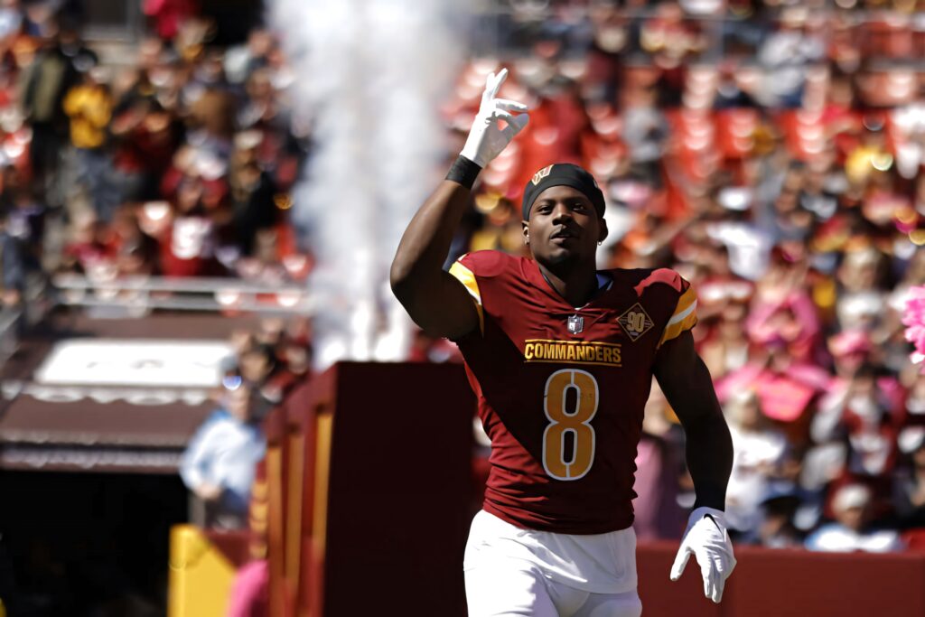 Brian Robinson Jr mid celebration in Commanders uniform number 8 with vibrant stadium crowd background Wallpaper