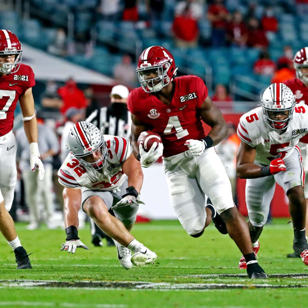 Brian Robinson Jr evasive football run in vibrant team colors high intensity college game action Wallpaper