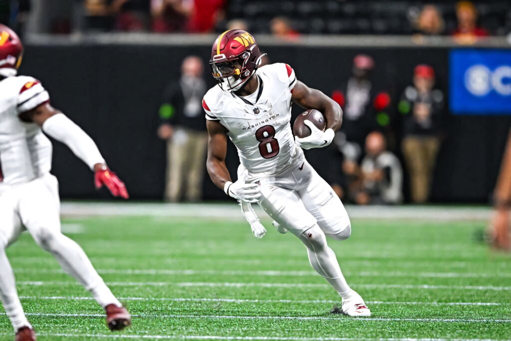 Brian Robinson Jr sprinting with football in full gear vibrant action shot wallpaper background