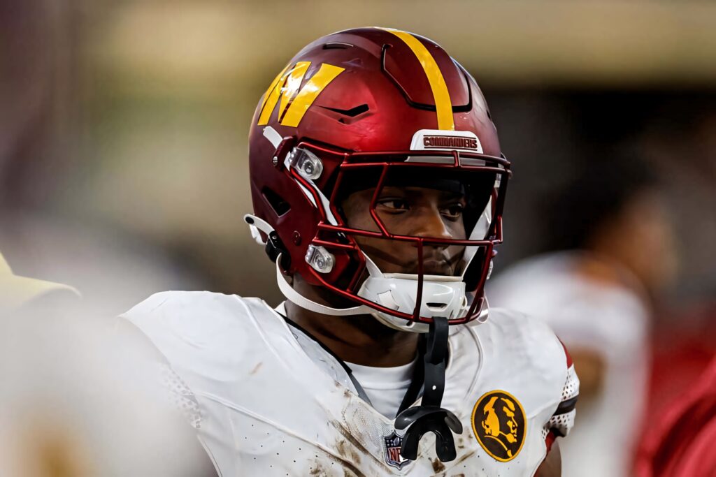 Focused Brian Robinson Jr football helmet number 8 with determined expression on vibrant field Wallpaper