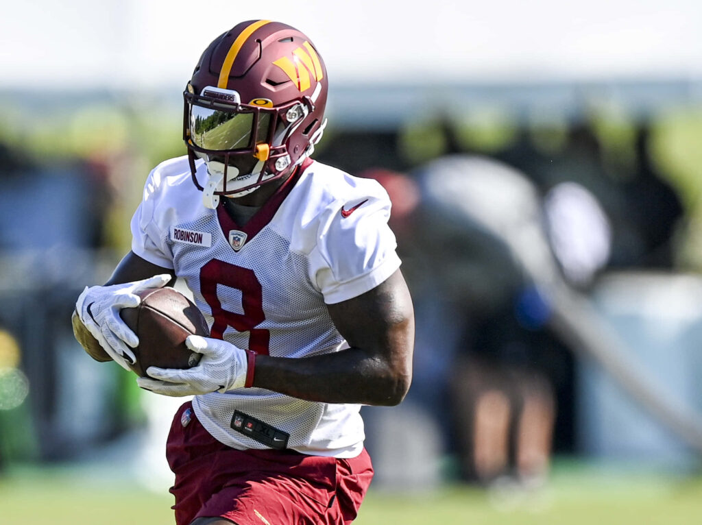 Brian Robinson Jr in maroon helmet carrying football during dynamic outdoor training session wallpaper