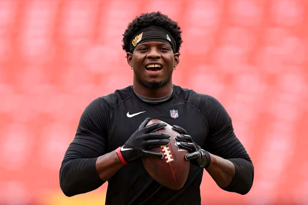 Brian Robinson Jr smiling confidently holding football stadium background high resolution wallpaper
