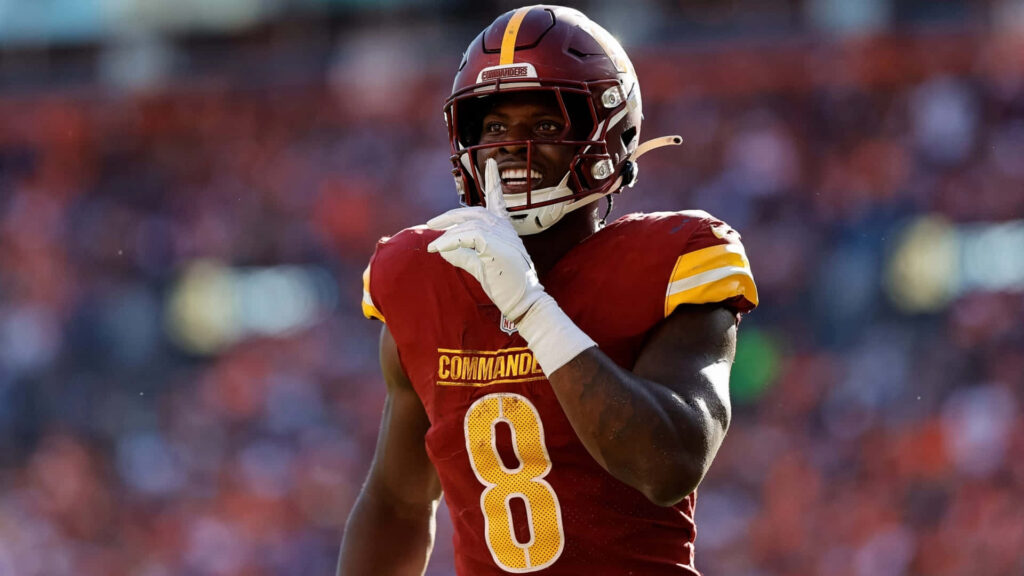 Brian Robinson Jr Washington Commanders in action burgundy gold uniform vibrant stadium background Wallpaper