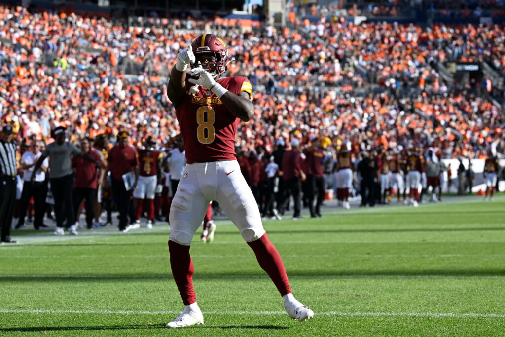 Brian Robinson Jr catching football game action in Washington Commanders burgundy gold uniform Wallpaper