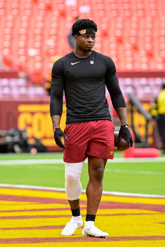 Brian Robinson Jr warming up in Washington Commanders burgundy gold gear at vibrant stadium Wallpaper