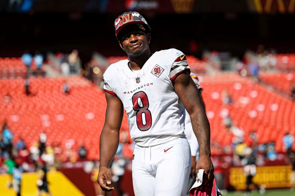 Washington Football Brian Robinson Jr in Commanders uniform on field with red stadium seats background Wallpaper