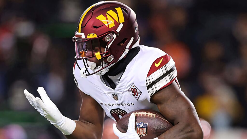 Brian Robinson Jr Washington Football Team running back in maroon and gold uniform charging forward Wallpaper