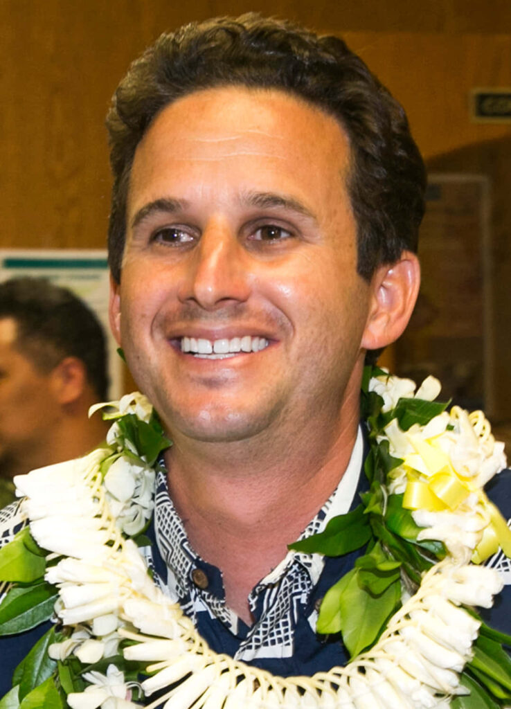 U.S. Senator Brian Schatz smiling warmly in high resolution portrait with Hawaiian lei and natural light Wallpaper