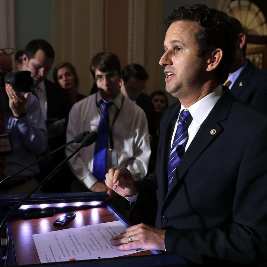 Brian Schatz speaking at Capitol press with journalists and photographers in government setting Wallpaper