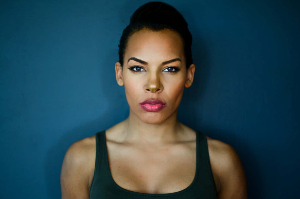 Brianna Goldie portrait wallpaper with confident expression vivid makeup deep blue background high resolution