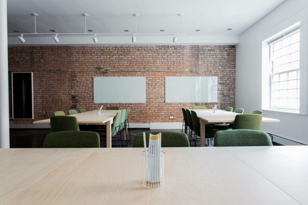 Brick-walled Meeting Oasis: Transform Your Zoom Meetings with a Green-Chair Haven Wallpaper
