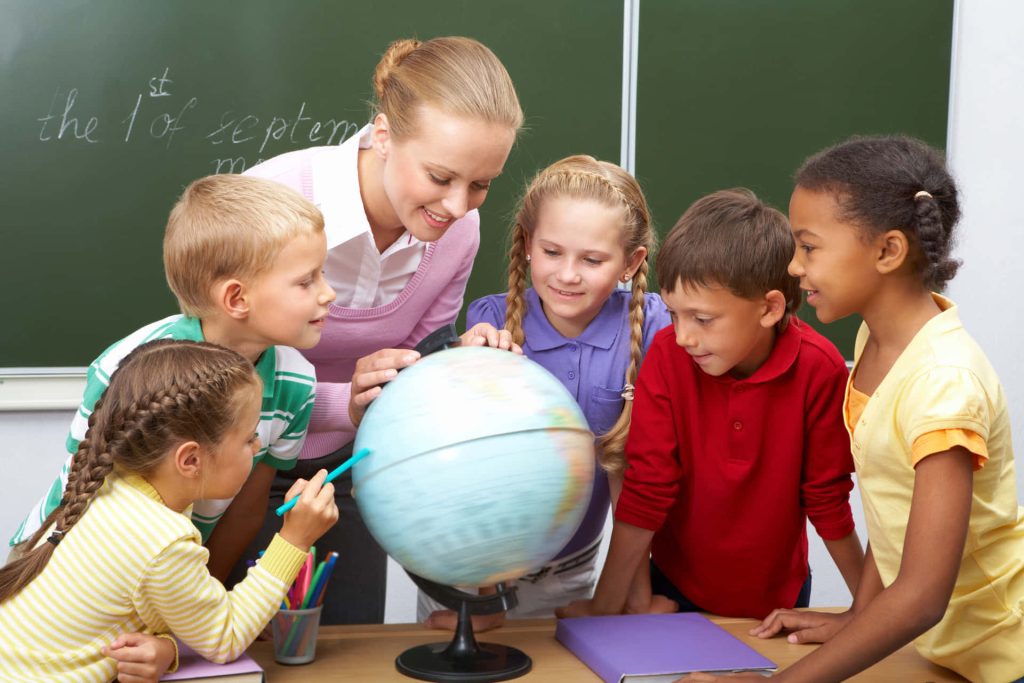 Smiling teacher and diverse students exploring globe in vibrant classroom learning wallpaper background