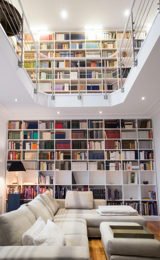 Bright white library with colorful books floor-to-ceiling shelves modern loft design cozy seating Wallpaper