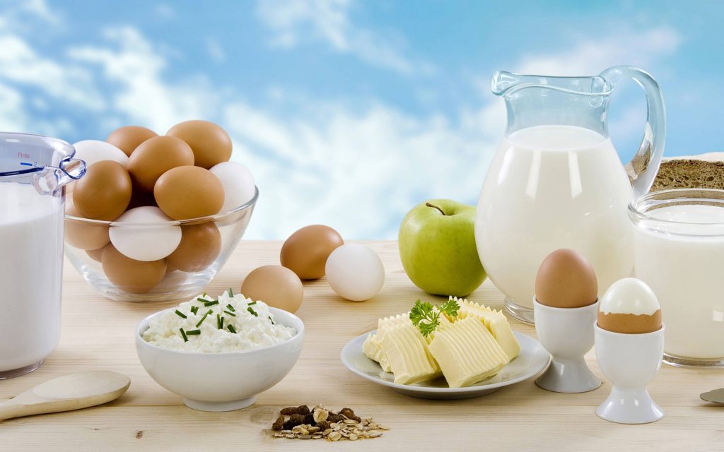 Bright breakfast spread with eggs milk cottage cheese butter apple and grains on wood table Wallpaper