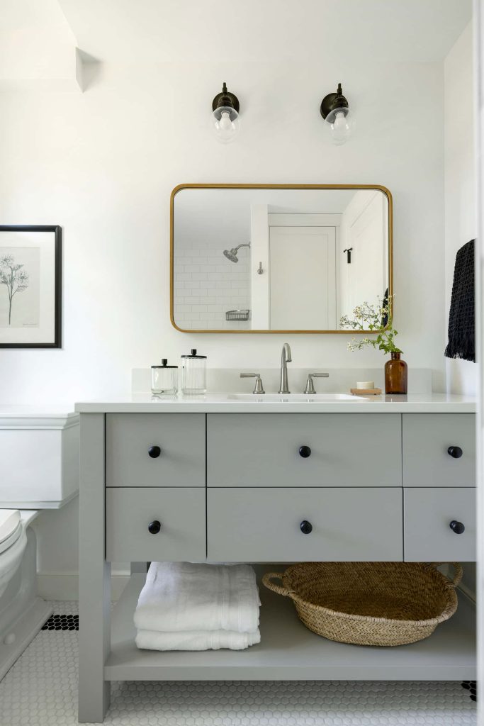 Bright modern bathroom with light grey vanity black hardware white hex tile and gold mirror Wallpaper