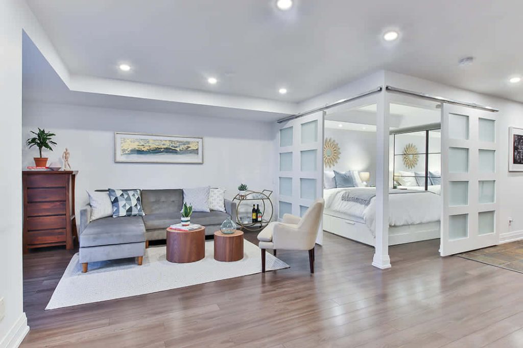 Bright modern living room with gray sectional sofa wood coffee tables and bar cart near bedroom Wallpaper