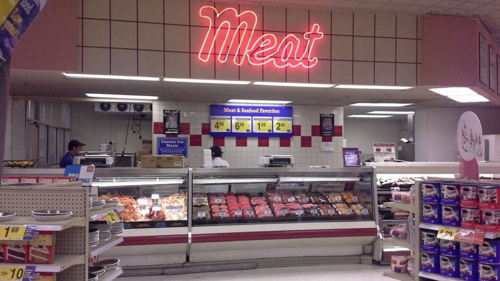 Bright neon Meat sign above fresh raw meat and seafood in brightly lit grocery store display case Wallpaper