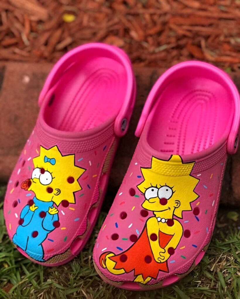 Bright pink Crocs with Lisa and Maggie Simpson illustrations and colorful confetti patterns Wallpaper