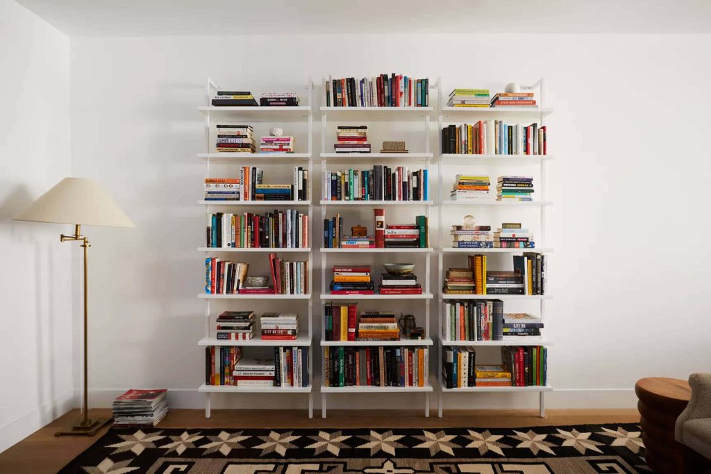 Bright modern home office Zoom background with white bookshelves colorful books and minimalist decor Wallpaper
