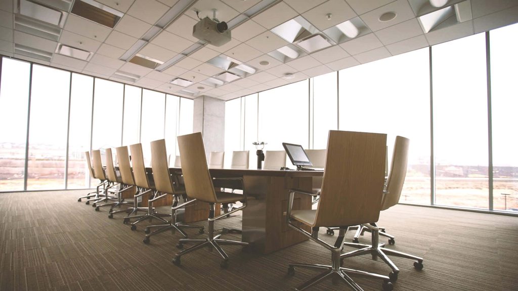 Bright spacious conference room with long table modern chairs and natural light windows background Wallpaper