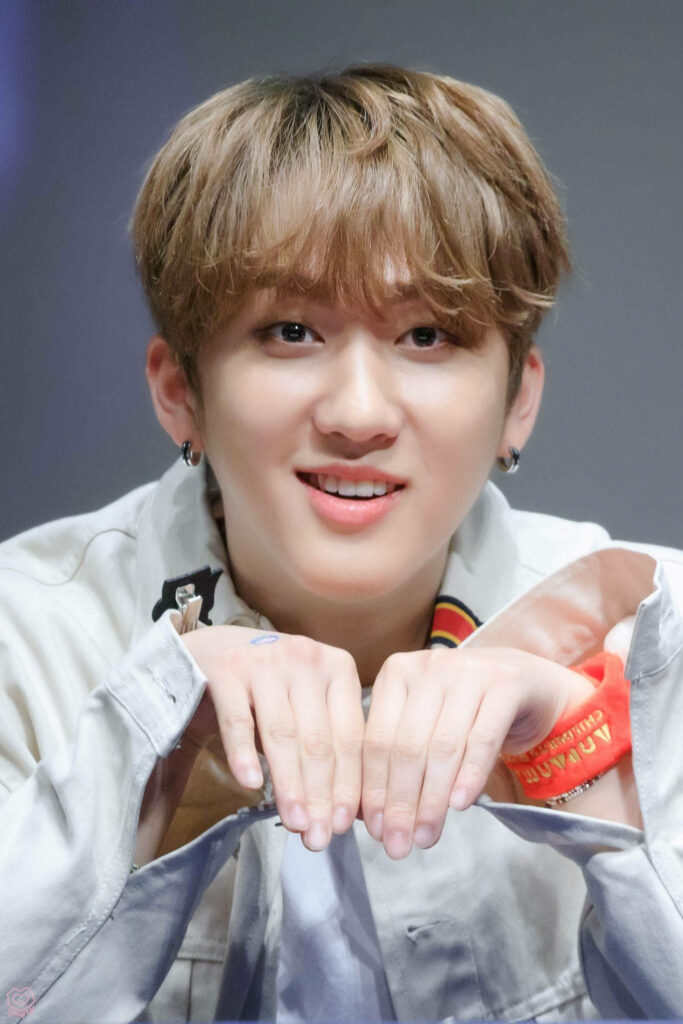 Bright Stray Kids member posing playfully in wallpaper background radiating warmth and charm