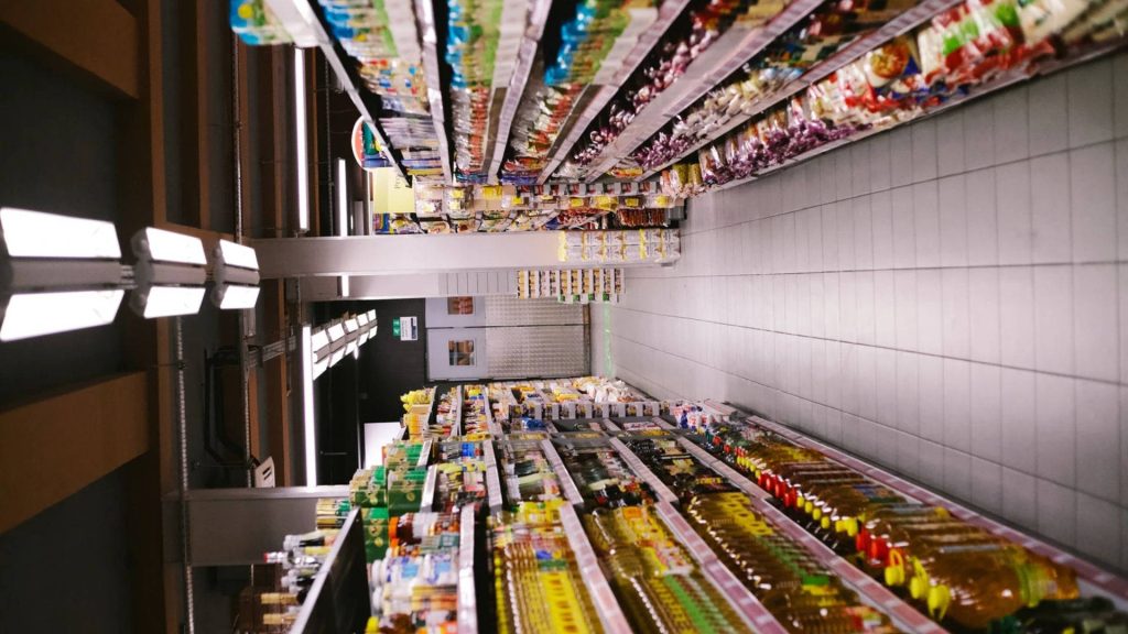 Vertically rotated photo of a well-organized grocery store aisle with bright shelves and products Wallpaper