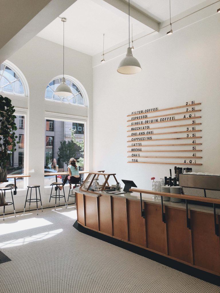 Bright white cafe with arched windows wooden counter woman relaxing minimalist menu board wallpaper