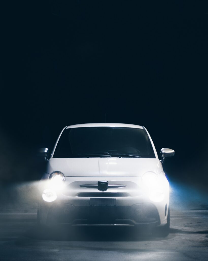 Front View of Bright White Car Illuminating Dark Background Wallpaper
