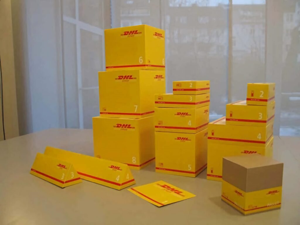 Bright yellow DHL delivery boxes of various sizes neatly arranged on smooth table for shipping Wallpaper