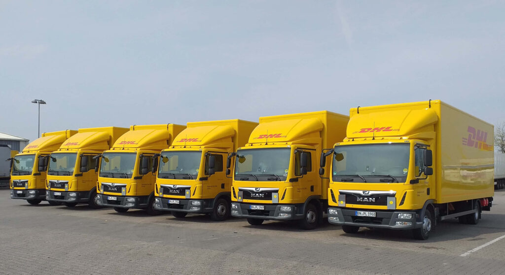 Row of bright yellow DHL delivery trucks parked showing fast efficient logistics and reliable service Wallpaper