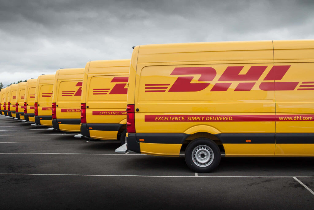 Fleet of bright yellow DHL vans with red branding in parking lot showcasing fast reliable shipping Wallpaper
