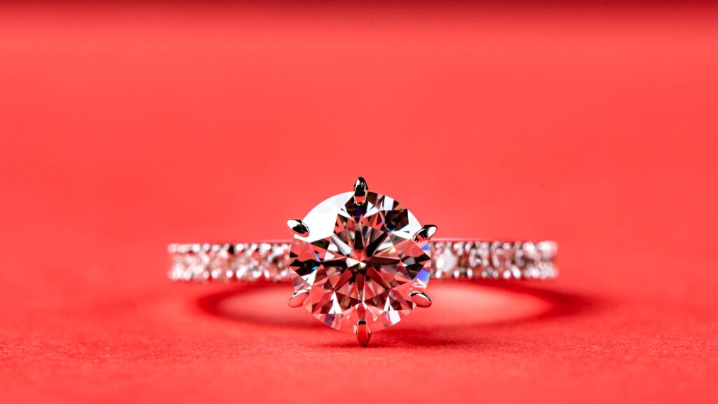 Brilliant diamond ring with crystal clarity and silver band on bold red luxury background wallpaper