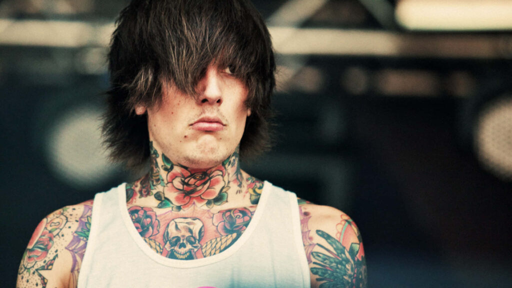 Tattooed Bring Me the Horizon musician performs on stage with vibrant tattoos and intense focus Wallpaper
