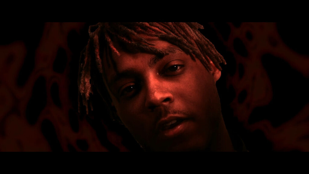 Intense Portrait of Late Rapper Juice Wrld with Striking Red Background Wallpaper