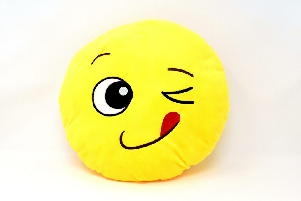 Joyful Cushion: An Exuberant Emoji Delight on Yellow Wallpaper