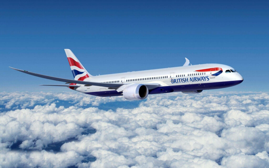 British Airways airplane side view flying above clouds with vibrant blue sky and branded tail fin Wallpaper